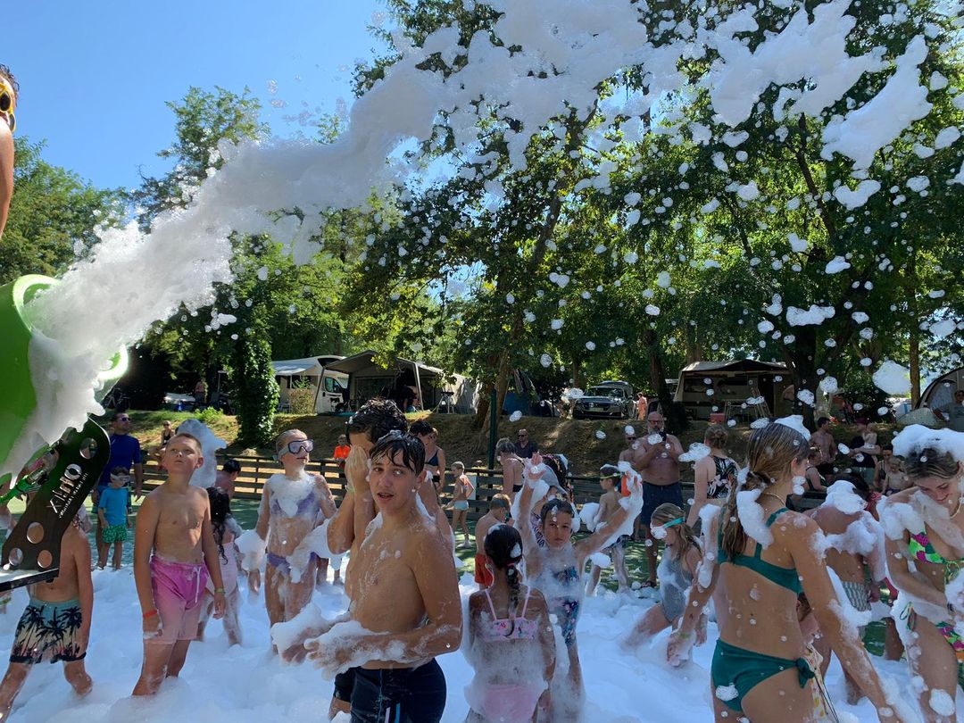 Kids playing under a foam cannon blast at a backyard foam party
