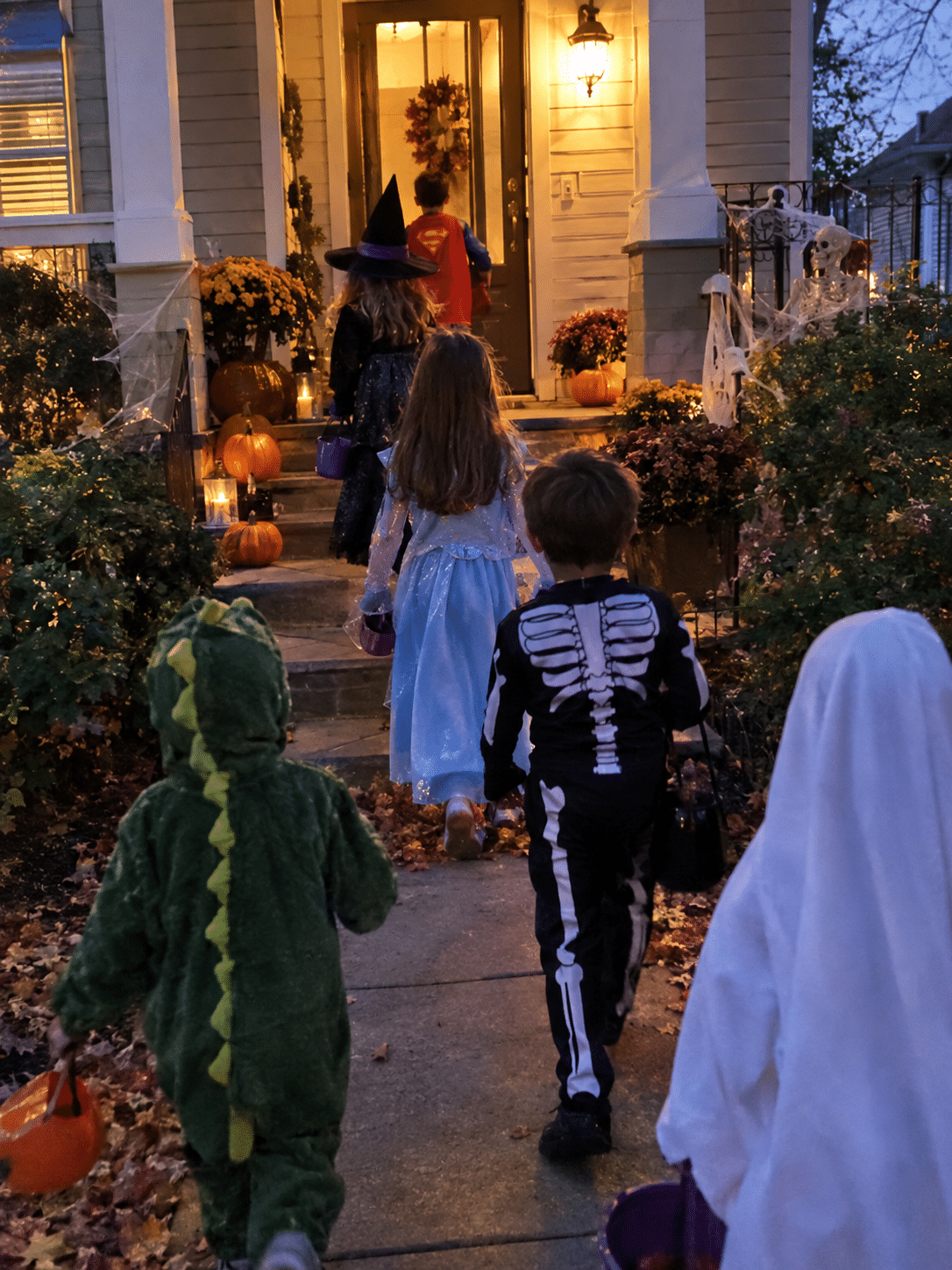 Kids in Halloween costumes trick-or-treating on a Newnan porch at dusk